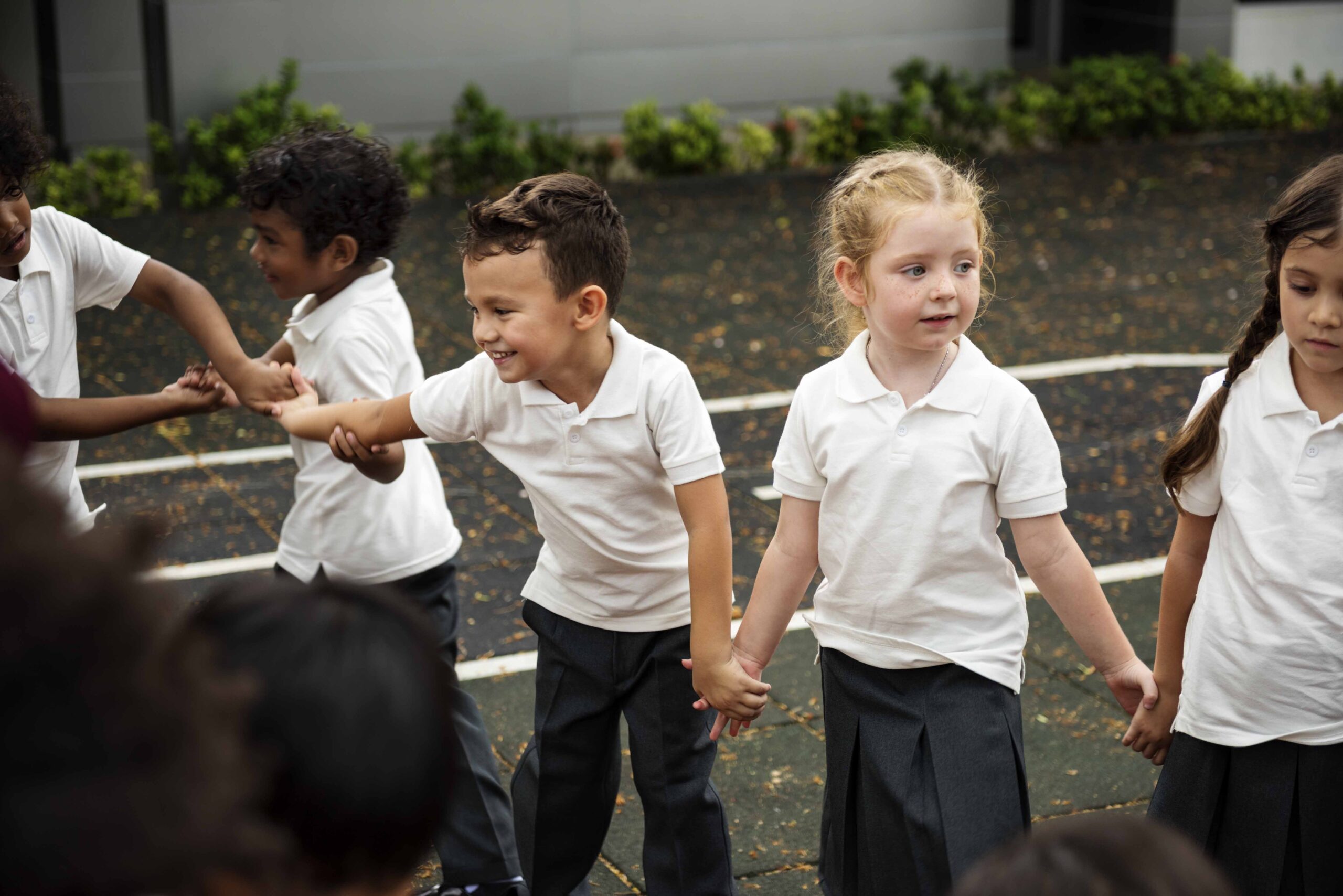 Group of diverse kindergarten students standing holding hands together